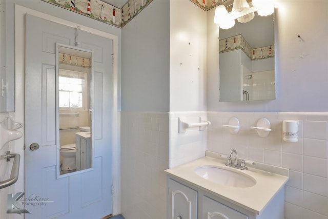 bathroom featuring vanity, toilet, and tile walls