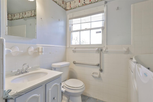 bathroom with vanity, toilet, tile walls, and a tub to relax in