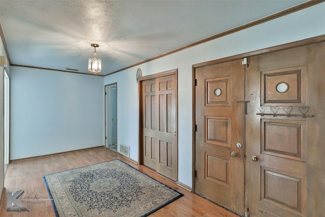 entrance foyer featuring crown molding and light wood-type flooring