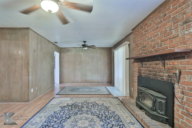 living room featuring ceiling fan, a wood stove, and light wood-type flooring