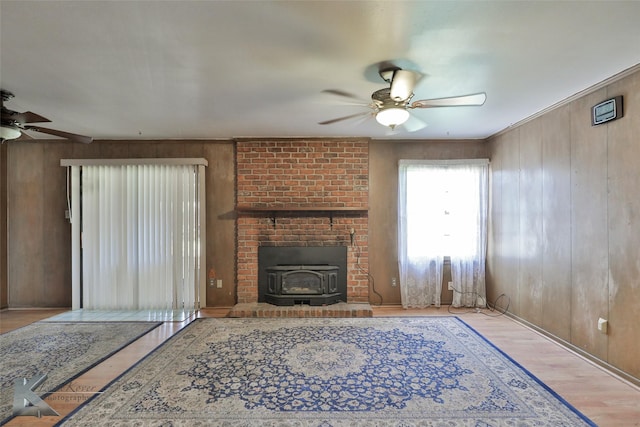 living room with ceiling fan, wooden walls, and light wood-type flooring