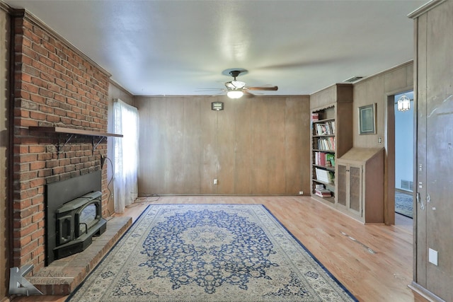 living room with light hardwood / wood-style floors, ceiling fan, and wood walls