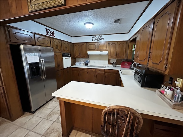 kitchen with sink, a textured ceiling, light tile patterned floors, kitchen peninsula, and black appliances