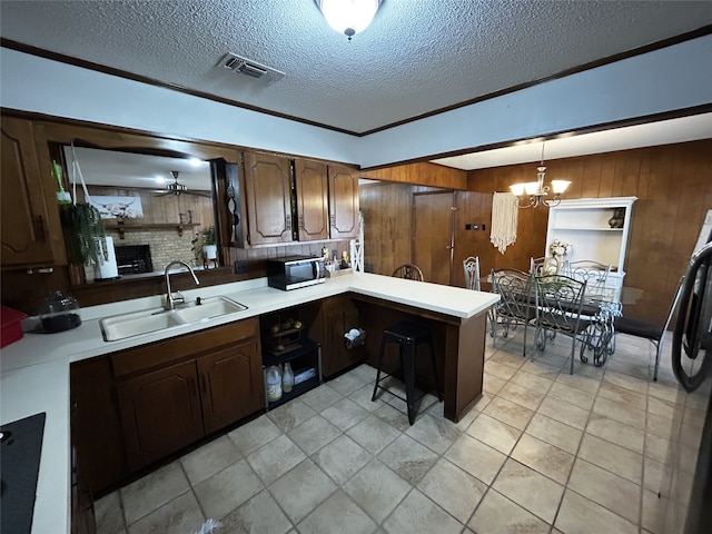 kitchen featuring pendant lighting, a fireplace, sink, kitchen peninsula, and black fridge