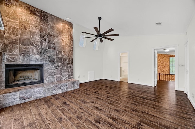 unfurnished living room with a stone fireplace, dark hardwood / wood-style floors, and ceiling fan