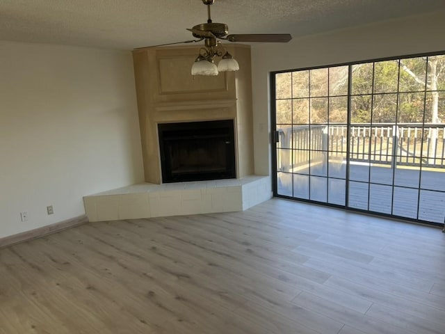 unfurnished living room with hardwood / wood-style flooring, ceiling fan, a fireplace, and a textured ceiling