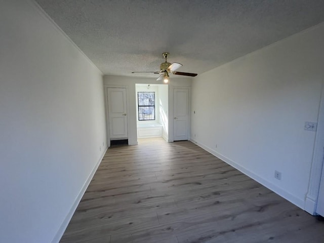 spare room with ornamental molding, ceiling fan, a textured ceiling, and light hardwood / wood-style floors