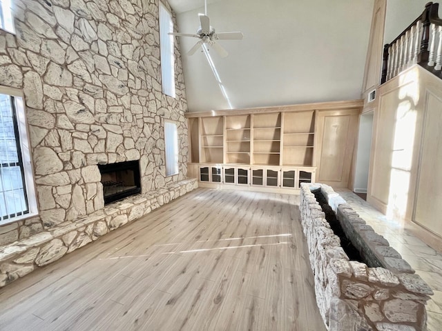 unfurnished living room with ceiling fan, a fireplace, high vaulted ceiling, and light hardwood / wood-style flooring