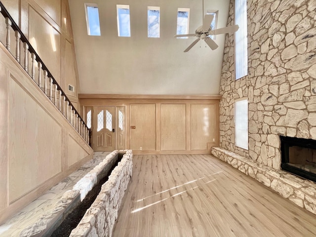 unfurnished living room with a stone fireplace, light hardwood / wood-style flooring, and ceiling fan