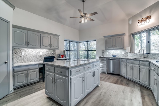 kitchen with dishwasher, sink, a kitchen island, and gray cabinetry