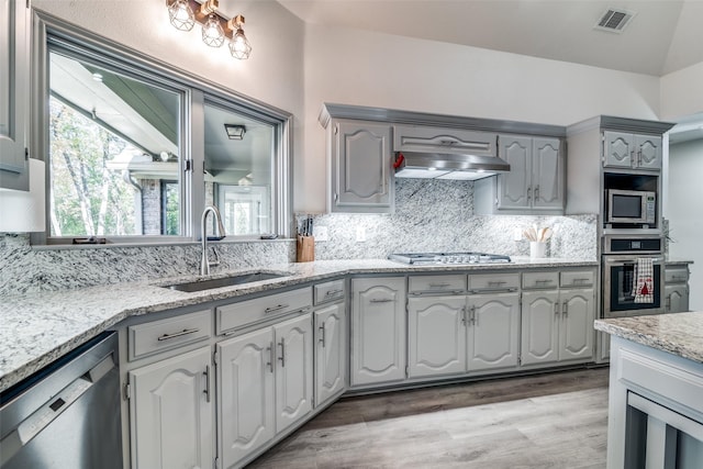 kitchen with sink, gray cabinetry, stainless steel appliances, ventilation hood, and decorative backsplash