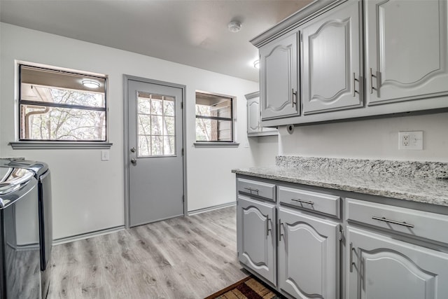 kitchen featuring electric stove, gray cabinets, light hardwood / wood-style floors, and light stone countertops