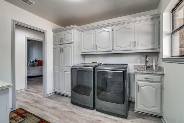 washroom with cabinets, independent washer and dryer, and light hardwood / wood-style flooring