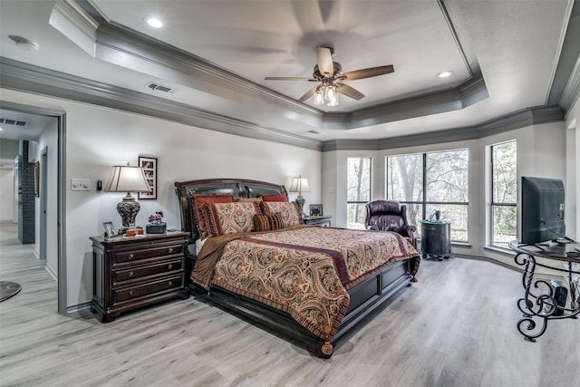 bedroom featuring crown molding, ceiling fan, light wood-type flooring, and a tray ceiling