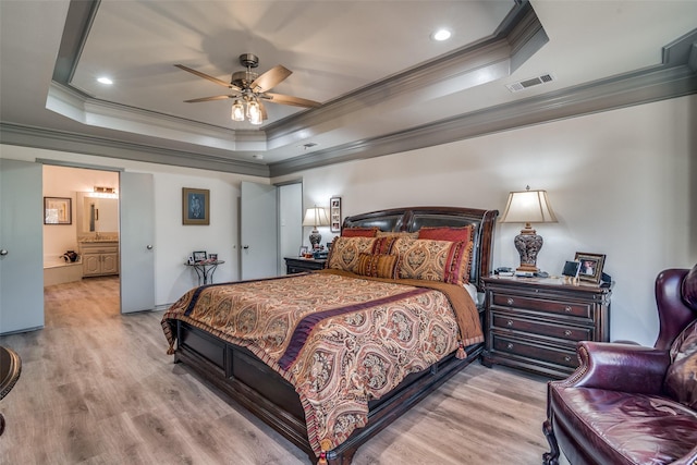 bedroom featuring a tray ceiling, ornamental molding, and light wood-type flooring