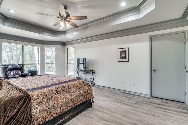 bedroom featuring a raised ceiling, crown molding, ceiling fan, and light hardwood / wood-style floors