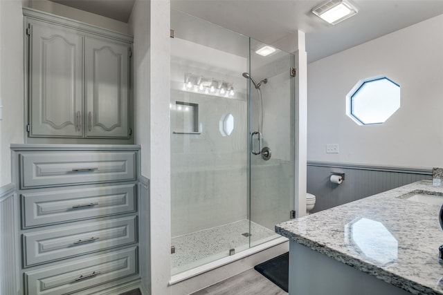 bathroom featuring a shower with door, vanity, wood-type flooring, and toilet