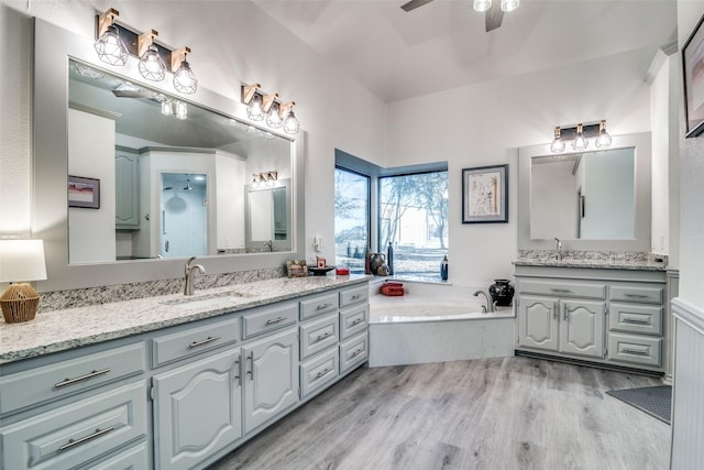 bathroom featuring vanity, wood-type flooring, a bath, and ceiling fan