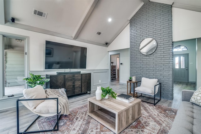 living room with beam ceiling, hardwood / wood-style floors, and high vaulted ceiling