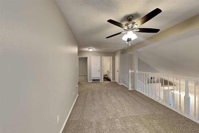 carpeted spare room with ceiling fan, vaulted ceiling, and a textured ceiling