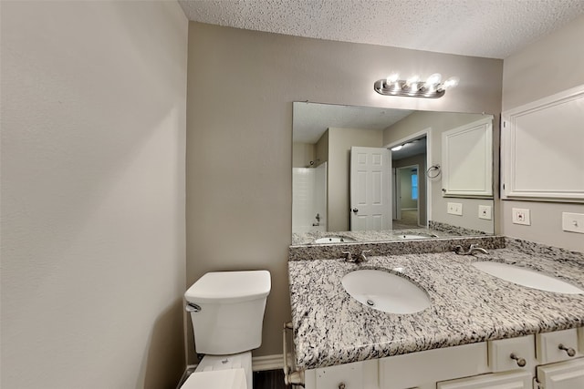 bathroom featuring walk in shower, vanity, a textured ceiling, and toilet