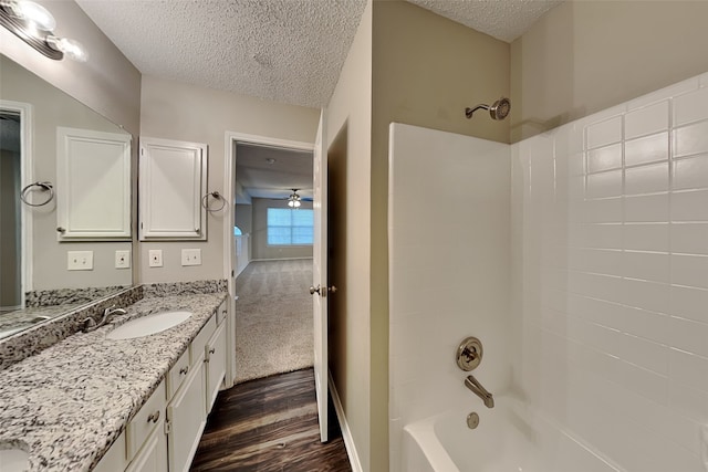 bathroom featuring  shower combination, wood-type flooring, a textured ceiling, vanity, and ceiling fan