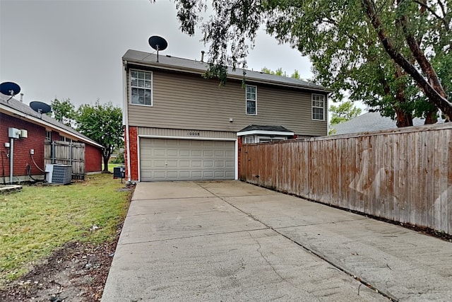 back of house featuring cooling unit, a yard, and a garage