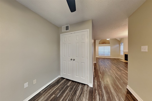 unfurnished bedroom with dark wood-type flooring, ceiling fan, a closet, and a textured ceiling