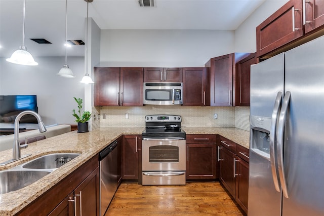 kitchen with sink, hardwood / wood-style flooring, decorative light fixtures, kitchen peninsula, and stainless steel appliances