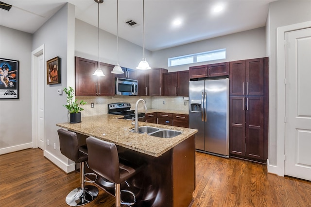 kitchen with dark hardwood / wood-style floors, kitchen peninsula, pendant lighting, a breakfast bar, and appliances with stainless steel finishes