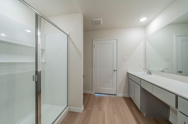 bathroom featuring hardwood / wood-style flooring, vanity, and a shower with shower door