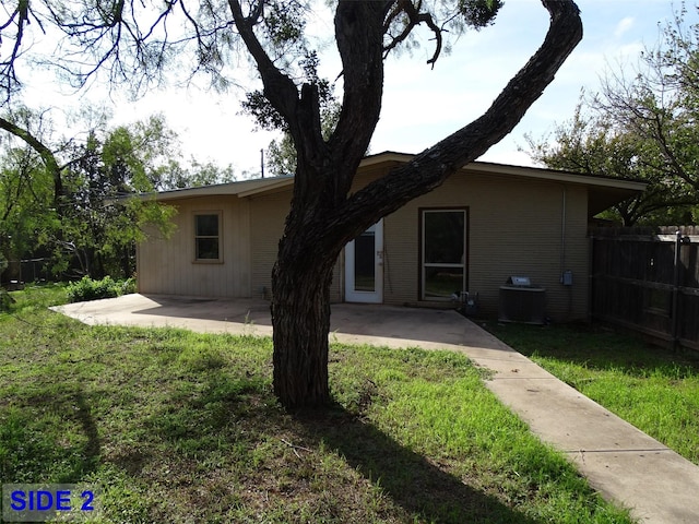 rear view of property featuring a yard, a patio, and central air condition unit