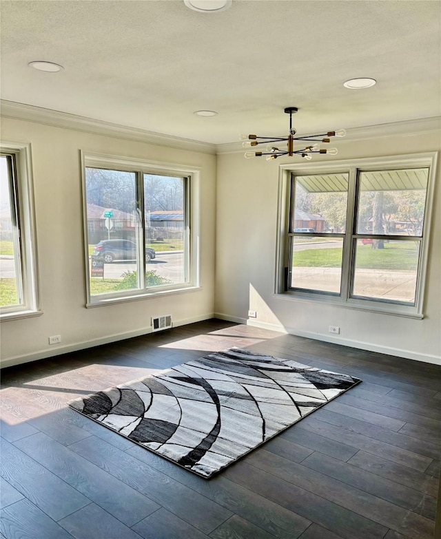 empty room featuring crown molding, a chandelier, and dark hardwood / wood-style flooring