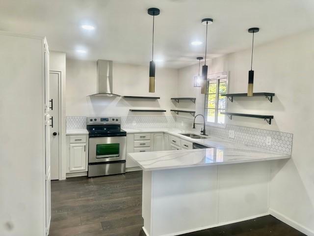 kitchen with kitchen peninsula, white cabinets, stainless steel electric range oven, and wall chimney exhaust hood