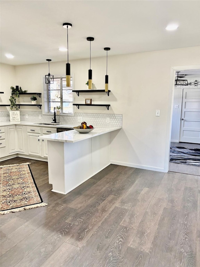 kitchen featuring sink, white cabinetry, dark wood-type flooring, kitchen peninsula, and hanging light fixtures