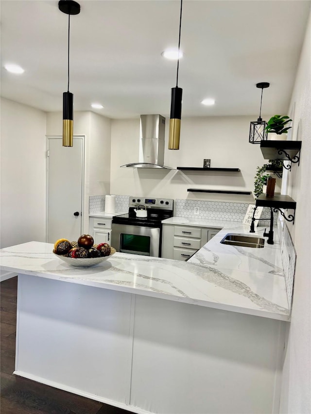 kitchen featuring kitchen peninsula, hanging light fixtures, sink, stainless steel electric stove, and wall chimney exhaust hood