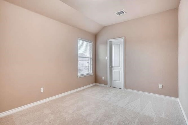 spare room featuring light colored carpet and vaulted ceiling