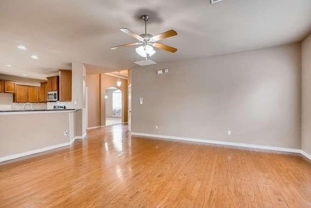 unfurnished living room with light wood-type flooring and ceiling fan