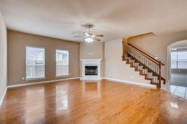 unfurnished living room with hardwood / wood-style floors, ceiling fan, and a healthy amount of sunlight