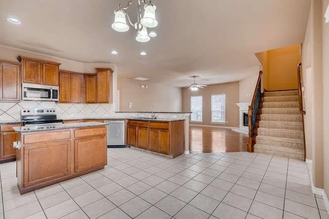 kitchen with appliances with stainless steel finishes, ceiling fan with notable chandelier, decorative light fixtures, and light tile patterned floors