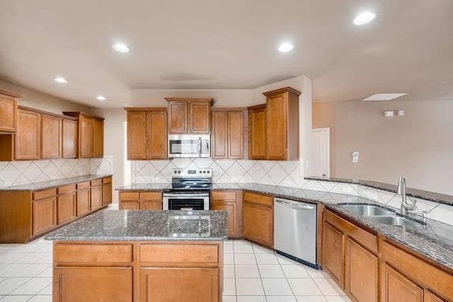 kitchen featuring a center island, dark stone counters, sink, appliances with stainless steel finishes, and tasteful backsplash