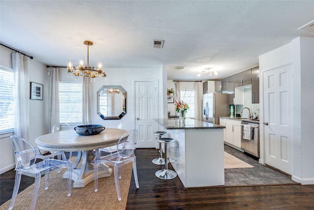 kitchen featuring appliances with stainless steel finishes, a breakfast bar area, a sink, and dark wood finished floors