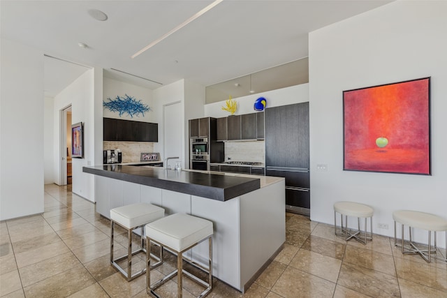 kitchen featuring a kitchen bar, decorative backsplash, sink, and appliances with stainless steel finishes