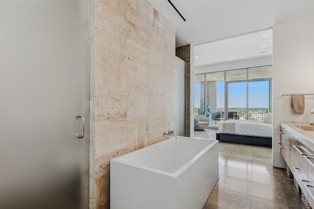 bathroom with tile patterned flooring, vanity, floor to ceiling windows, and tile walls