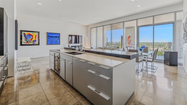 kitchen with light stone countertops, a center island with sink, a wealth of natural light, and sink