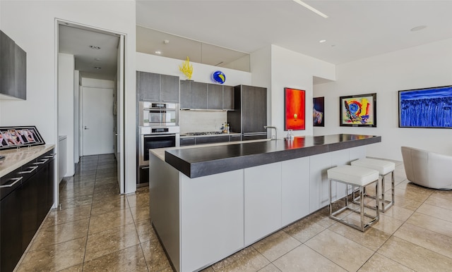 kitchen with sink, stainless steel appliances, backsplash, a breakfast bar area, and a kitchen island