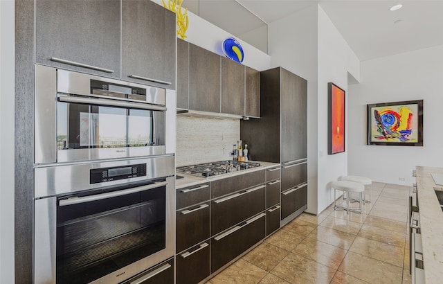 kitchen featuring dark brown cabinets, backsplash, and stainless steel appliances