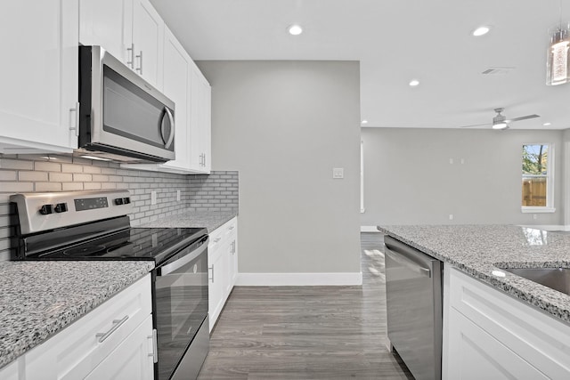 kitchen with appliances with stainless steel finishes, light stone counters, ceiling fan, white cabinets, and hardwood / wood-style floors