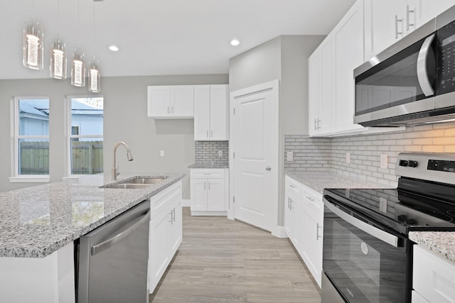 kitchen featuring appliances with stainless steel finishes, a kitchen island with sink, sink, light hardwood / wood-style flooring, and white cabinetry