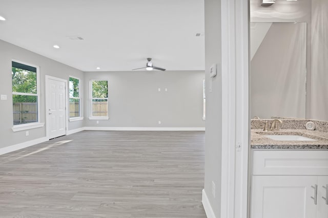 unfurnished living room featuring ceiling fan, sink, and light hardwood / wood-style floors